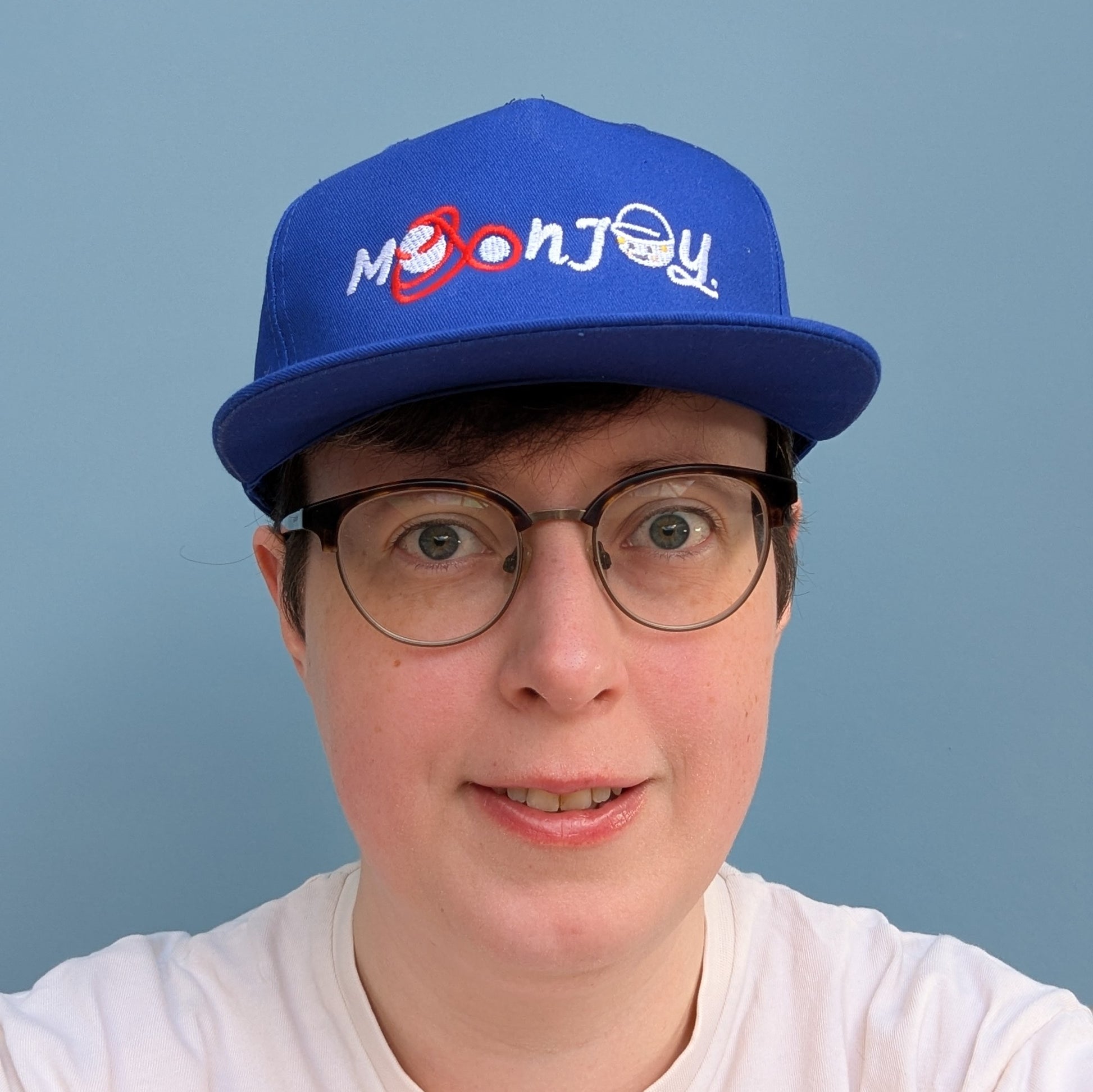 Person wearing blue cap with 'Moon Joy' text, featuring a red route and Rise, against a light background